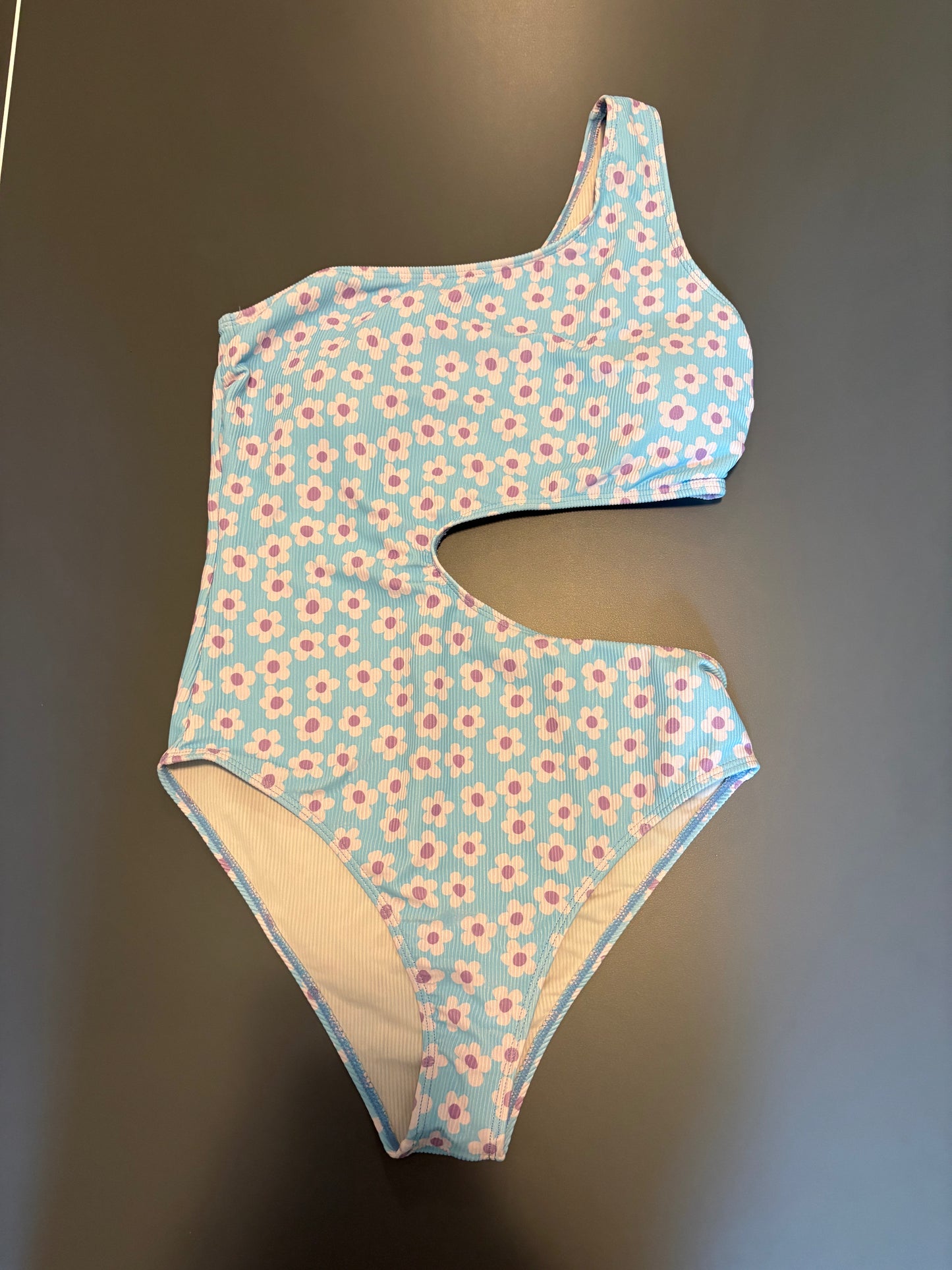blue one piece bathing suit with purple flower accents and open side